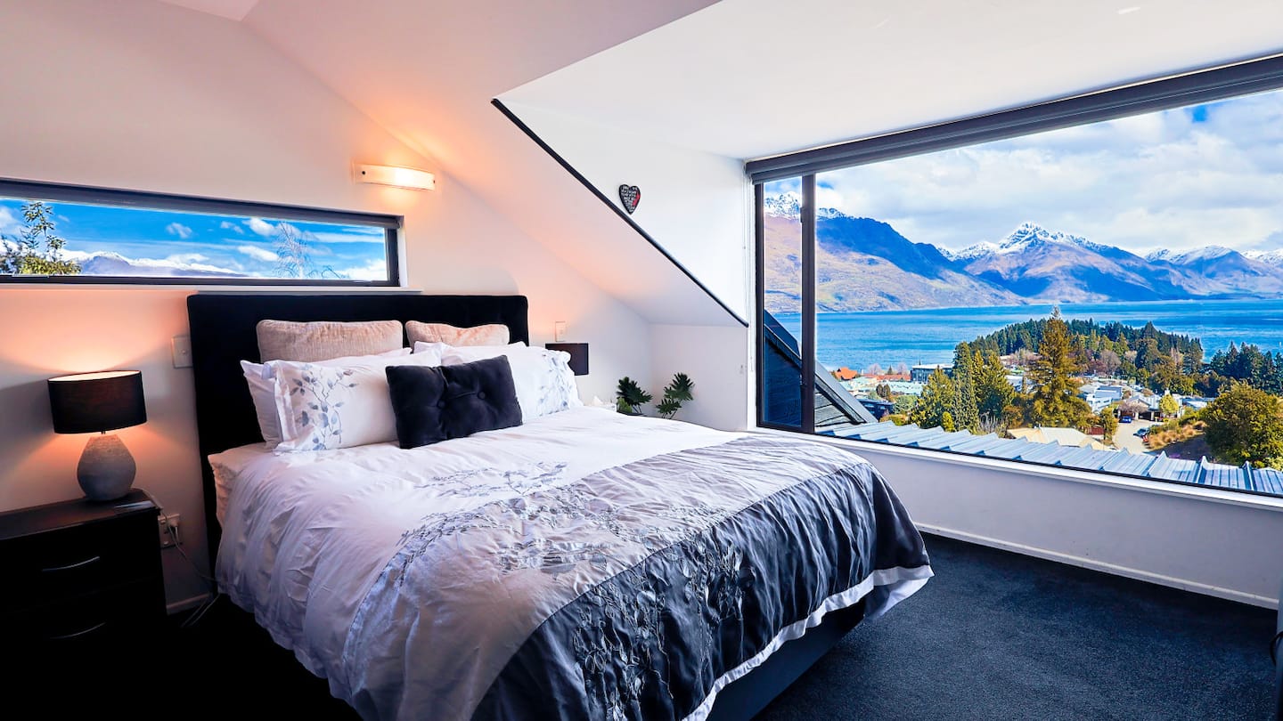 Hilltop Studio bedroom with wide windows framing Lake Wakatipu and the mountains